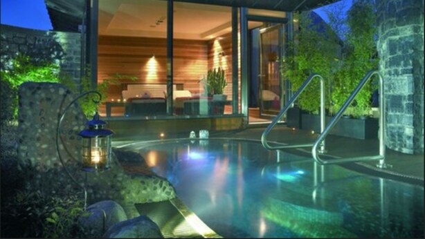 Uma casa moderna com piscina envidraçada, paredes de pedra e interior em madeira.