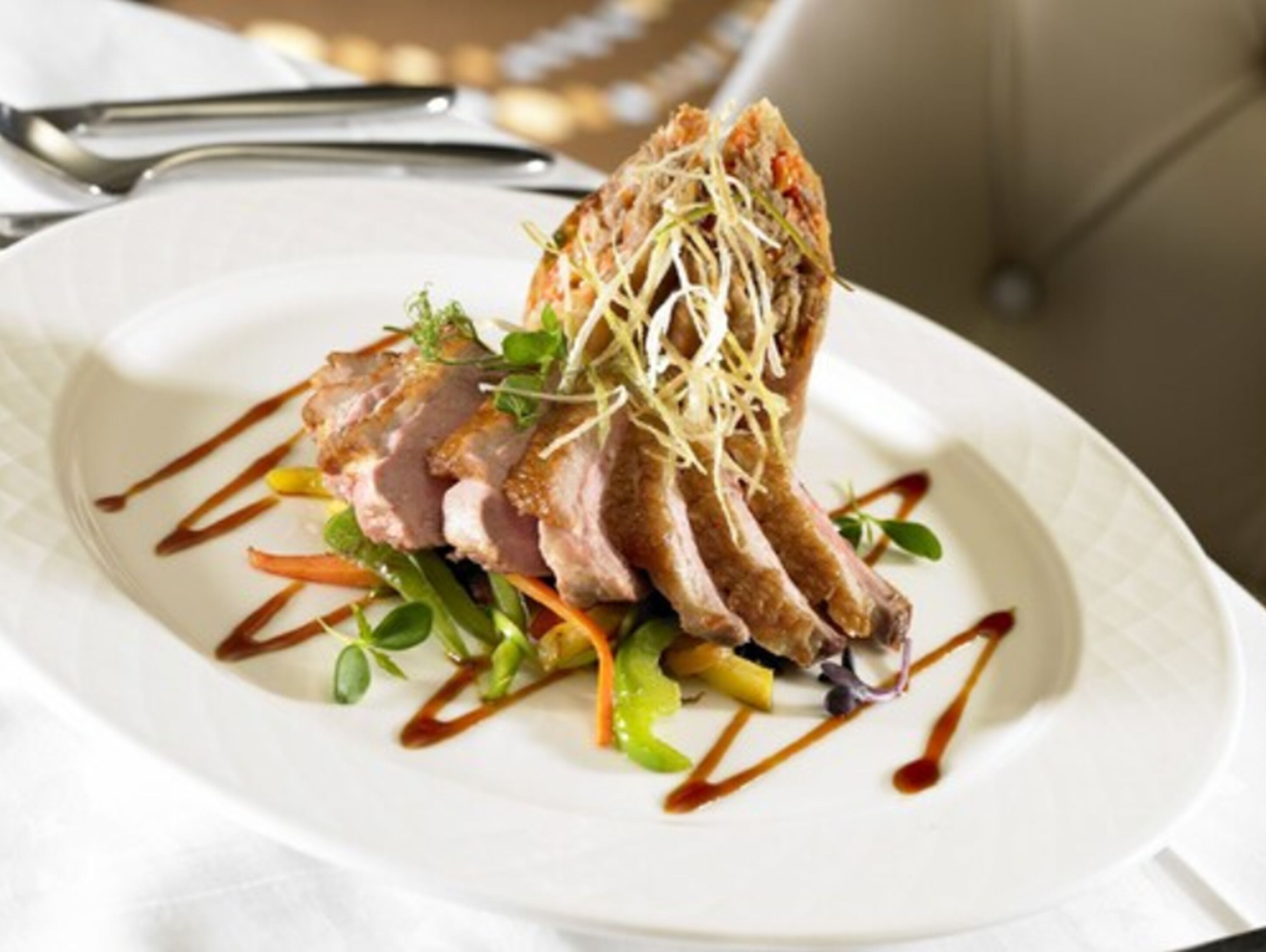 Une assiette de nourriture comprenant de la viande coupée en tranches, des légumes et un peu de sauce.