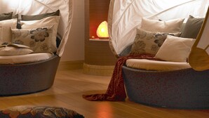 Quarto moderno com duas cadeiras suspensas, lareira e piso de madeira.