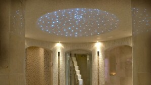 Um quarto de spa com teto estrelado, uma escadaria e duas áreas de estar com almofadas.