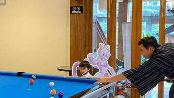 A pool table with balls, a person playing, and a child watching.