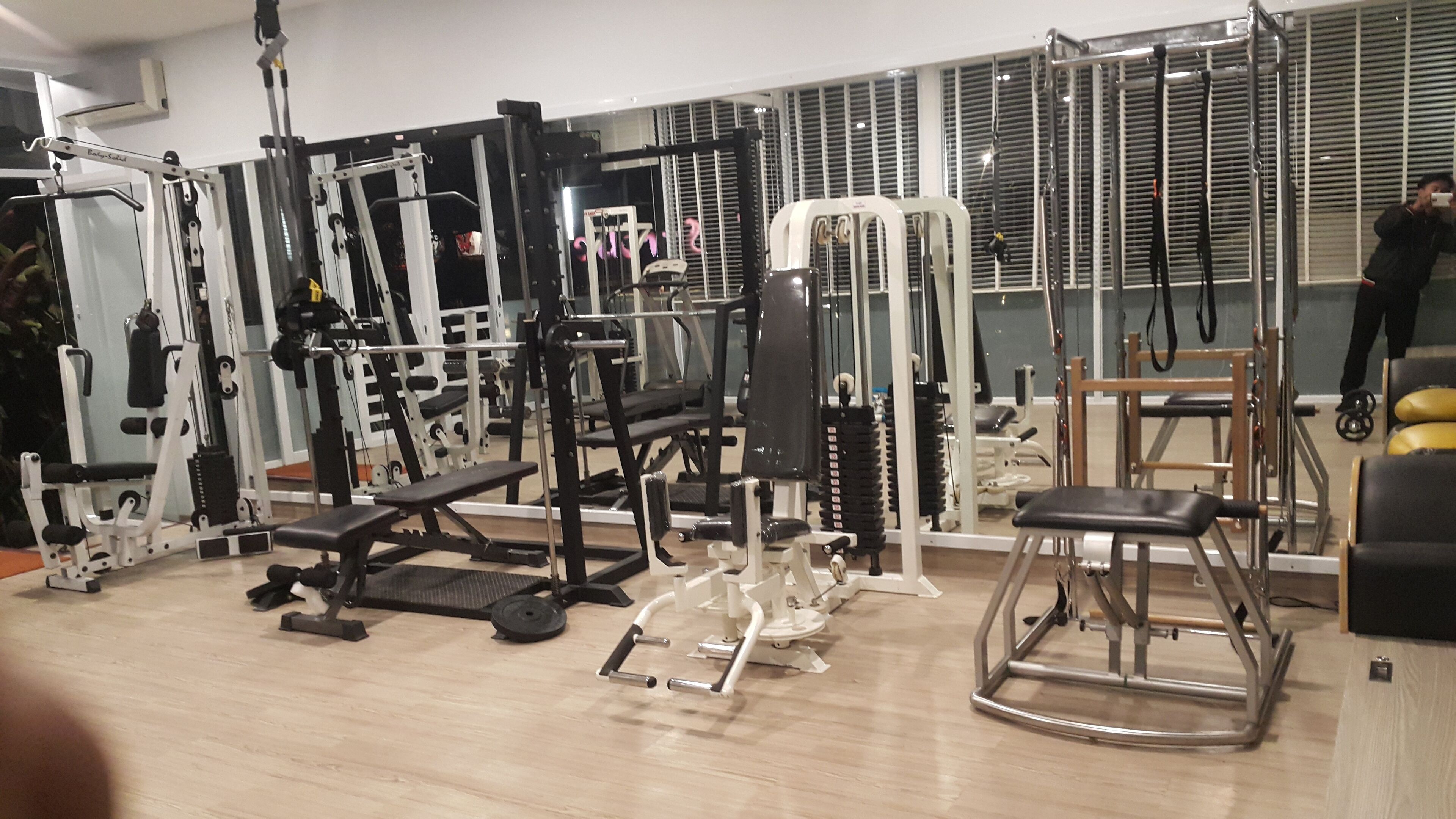 Et fitnesscenter med forskellig træningsudstyr, herunder styrkemaskiner og håndvægte.