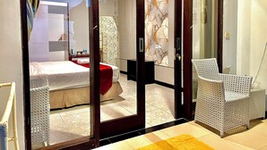 Een moderne hotelkamer met een bed, een rode accentstoel en een grote spiegel.