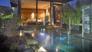 Une maison moderne dotée d’un salon entièrement vitré, d’une piscine et d’un mur en pierre.