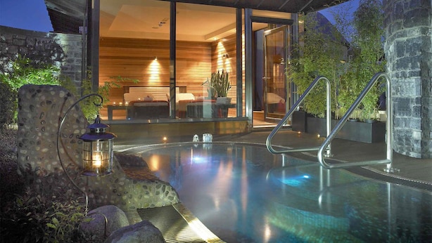 Een modern huis met een glazen woonruimte, een zwembad en een stenen muur.