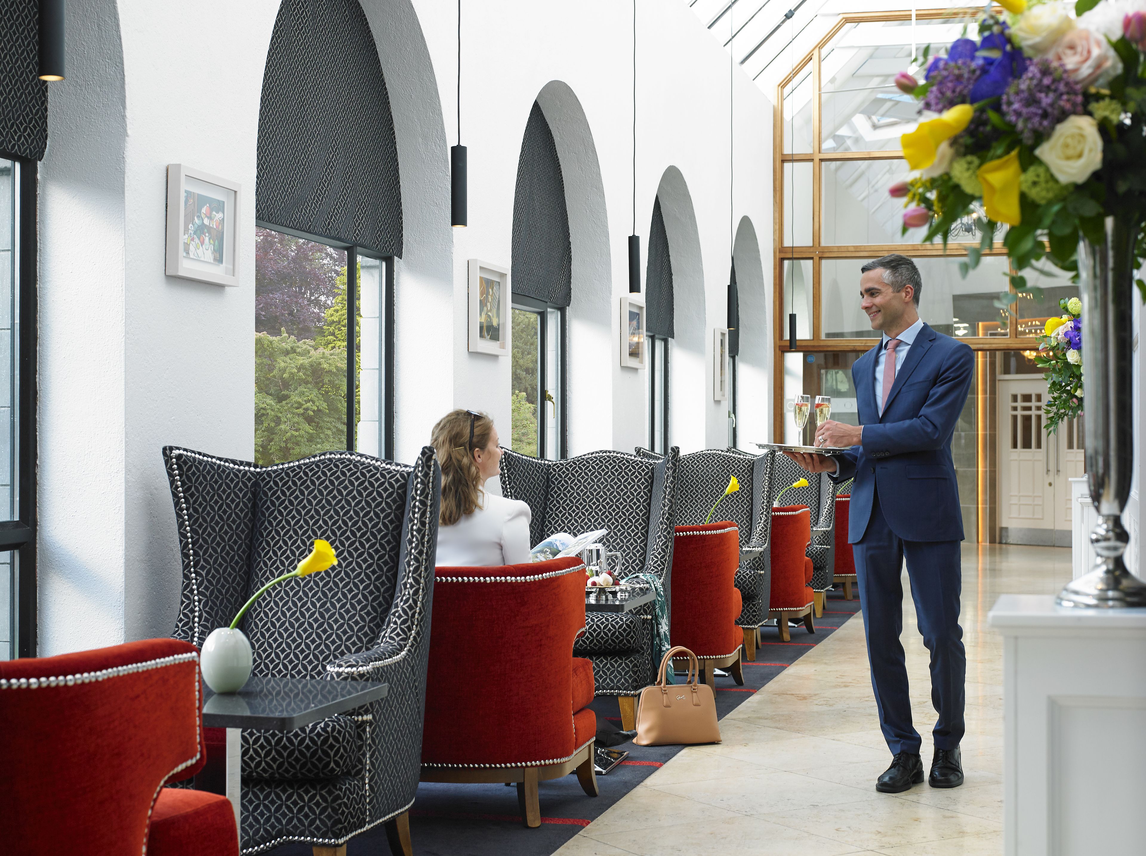 Un vestíbulo de hotel con sillas estampadas, una zona de recepción y vistas al exterior.