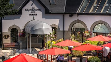 Relax in the hotel's outdoor seating area with comfortable wicker furniture under a covered space.