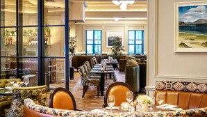 Een restaurant met een lange tafel, zachte zitplaatsen en uitzicht op de omgeving.