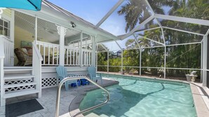 A pool area with a covered deck, chairs, and a clear view of the surrounding greenery. - Top-Rated Marco Beach House, Heated Pool, Bikes, Walk to Beach & JW Marriott (Marco Island)