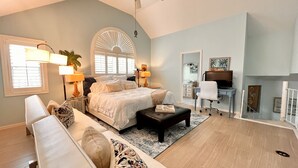 A spacious bedroom with a large bed, a desk, and a chair. There is a window with blinds, a lamp, and a plant. - Top-Rated Marco Beach House, Heated Pool, Bikes, Walk to Beach & JW Marriott (Marco Island)