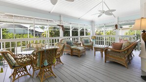 A covered outdoor patio with wicker furniture, ceiling fans, and large windows. - Top-Rated Marco Beach House, Heated Pool, Bikes, Walk to Beach & JW Marriott (Marco Island)