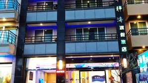 A multi-story hotel with a prominent entrance, a staircase leading to the entrance, and a signboard with text. - Tranquil Sea Hotel (Hengchun)