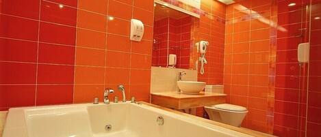 Un baño con una bañera grande, un lavamanos y un inodoro.