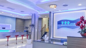 A hotel reception area with a modern design, featuring a reception desk, a digital display, and a staircase. - Tranquil Sea Hotel (Hengchun)