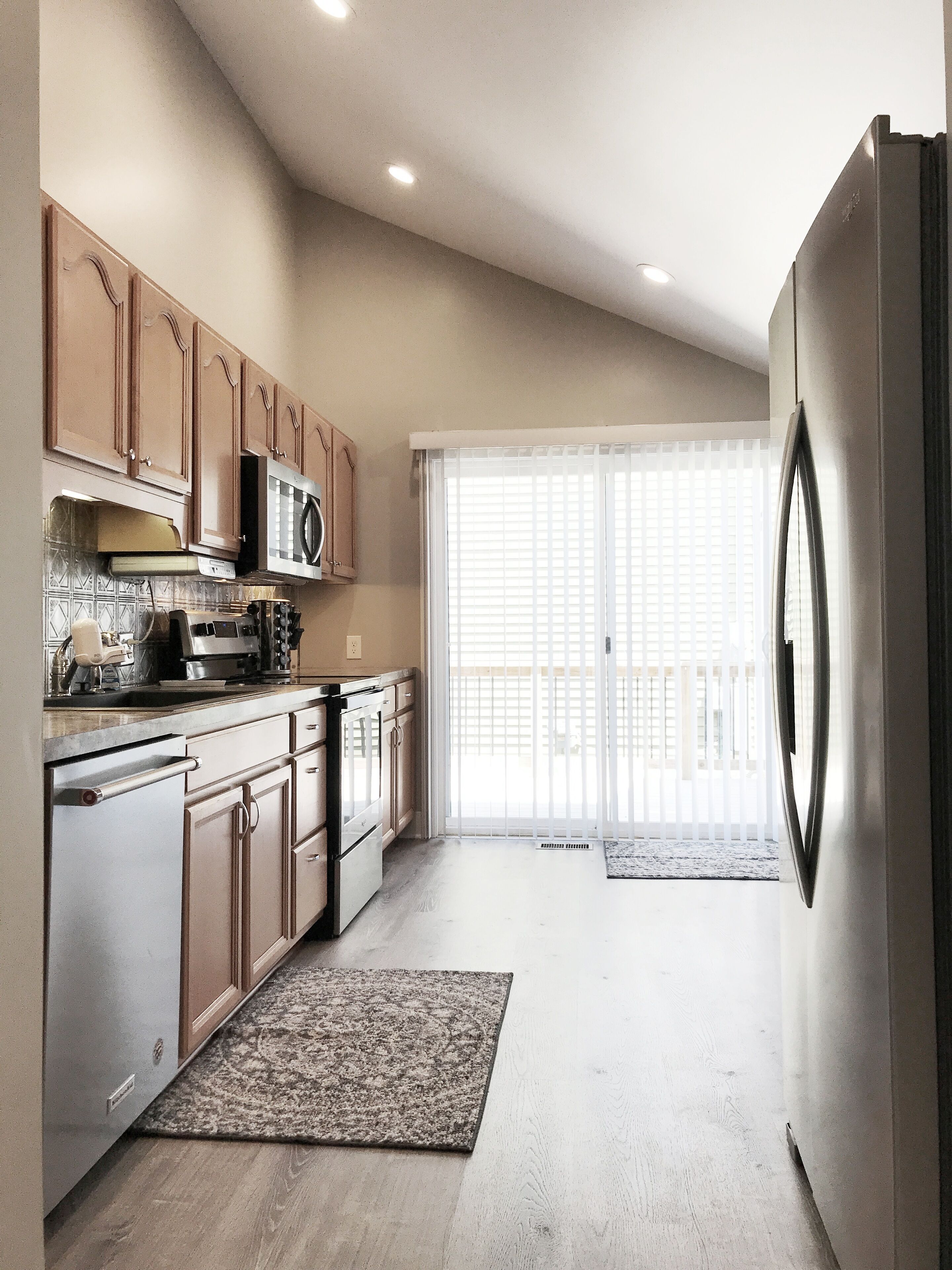 A modern kitchen with wooden cabinets, stainless steel appliances, and a large refrigerator.