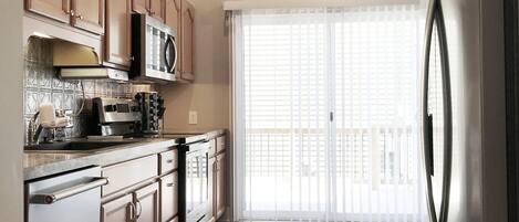 A modern kitchen with wooden cabinets, stainless steel appliances, and a large refrigerator.