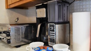 Une cuisine équipée d’une machine à café, de deux tasses et d’un distributeur d’essuie-tout.