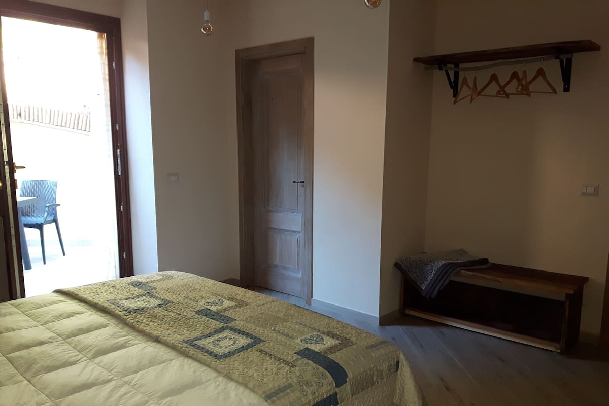 Une chambre à coucher avec un lit, un banc, une porte et un porte-vêtements.