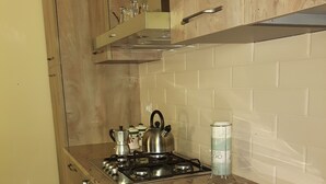 A kitchen with wooden cabinets, a stainless steel stove, and a tiled backsplash. - B&B da Morena (Minucciano)