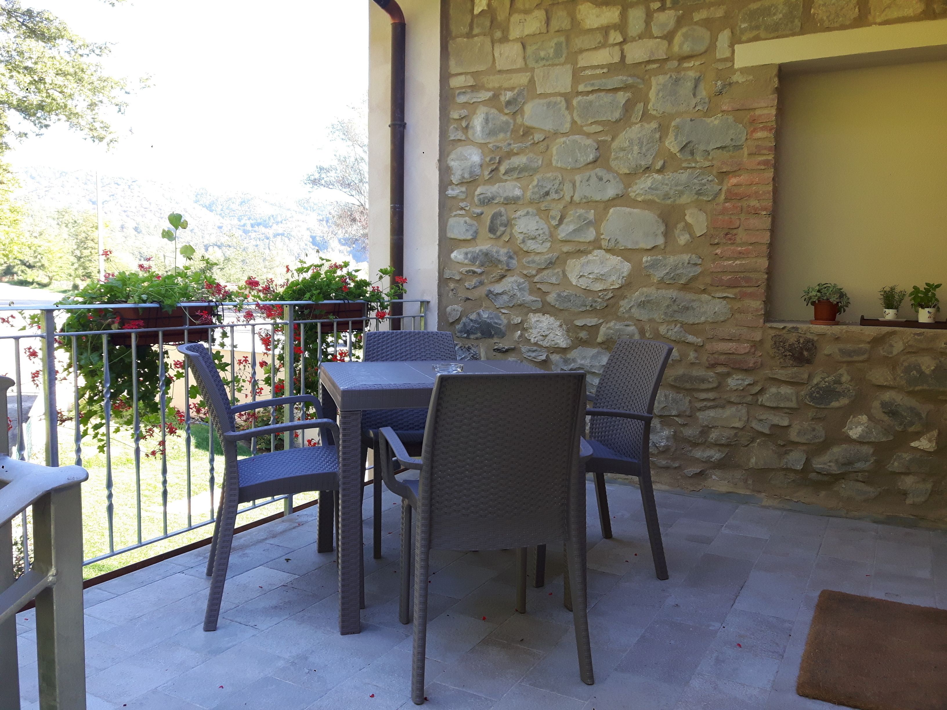 Une terrasse extérieure avec un mur en pierre, une table et des chaises.