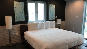 Una habitación de hotel moderna con una cama grande, dos lámparas de noche y obras de arte en las paredes.