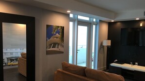 Una sala de estar moderna con un sofá, un cuadro de un edificio, un espejo grande y un televisor.