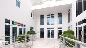 Un edificio moderno con fachada blanca, una tienda con el rótulo "Italian Gelato" y una entrada protegida por una reja.