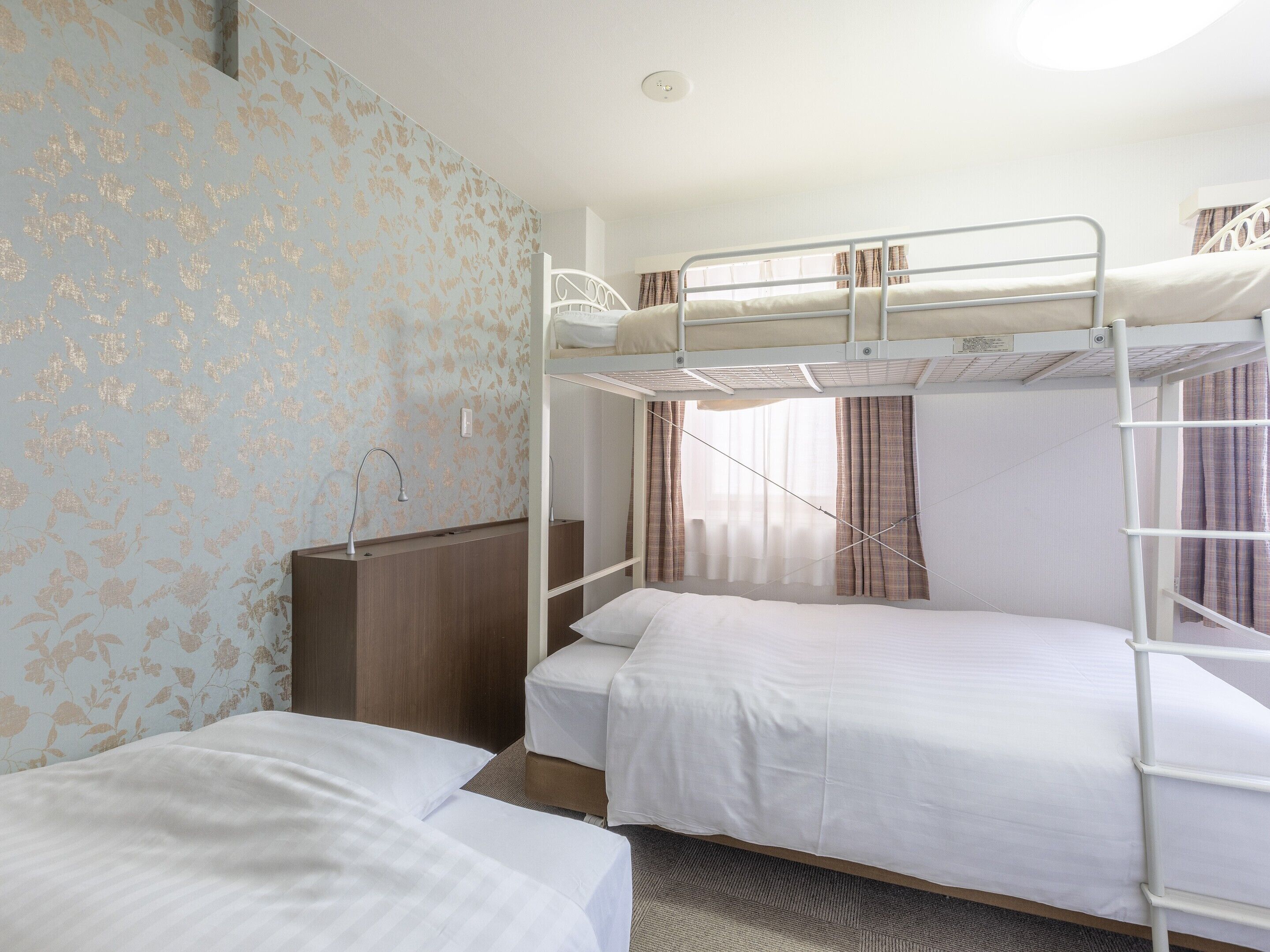 Quarto com beliche, cômoda de madeira e janela com cortinas.