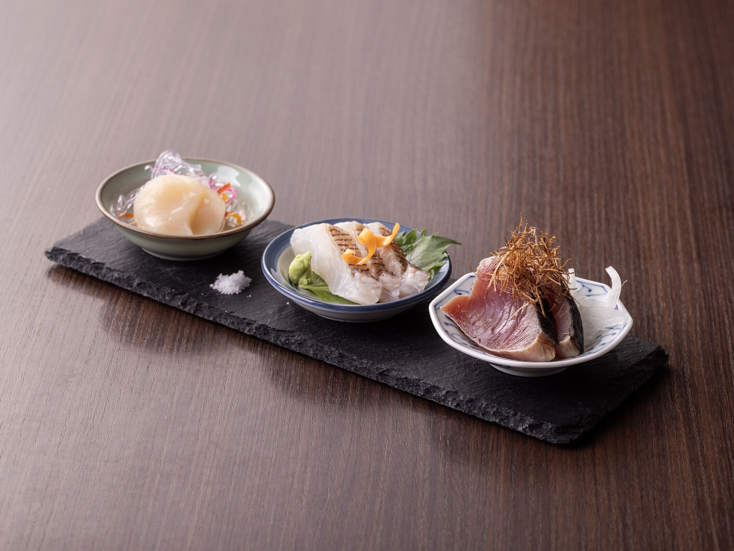 Three dishes on a slate serving board.