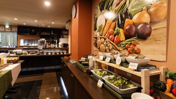 Un área de bufé con diversas opciones de comida y un amplio mural en la pared con motivos vegetales.