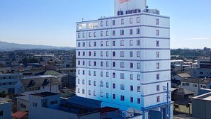 Un edificio de varios pisos con fachada uniforme, numerosas ventanas y una antena en el techo.