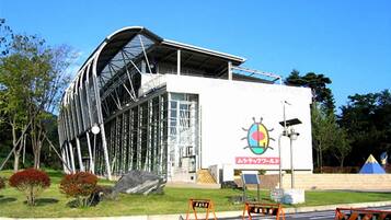 A modern building with a curved glass facade, a large entrance, and a sign with a colorful logo.