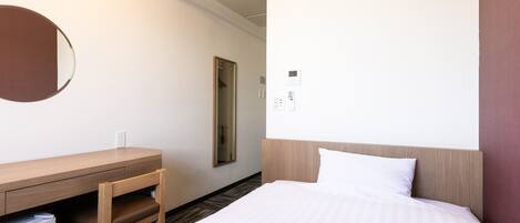 Quarto de hotel com cama, escrivaninha, espelho e ar condicionado.