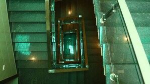A modern staircase with glass railings and dark marble steps.