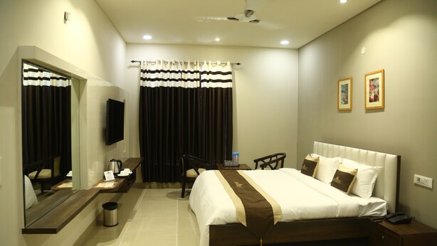 A hotel room with a bed, bedside table, chair, and a TV mounted on the wall.