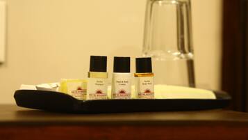 A tray with three bottles of BHUMI RESIDENCE products and a glass bottle on a wooden surface.