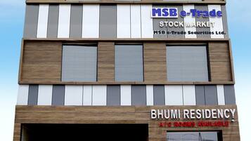 Un immeuble à plusieurs étages, avec une enseigne indiquant « MSB e-Trade, MARCHÉ BOURSIER » et « BHUMI RESIDENCY », proposant des chambres climatisées.