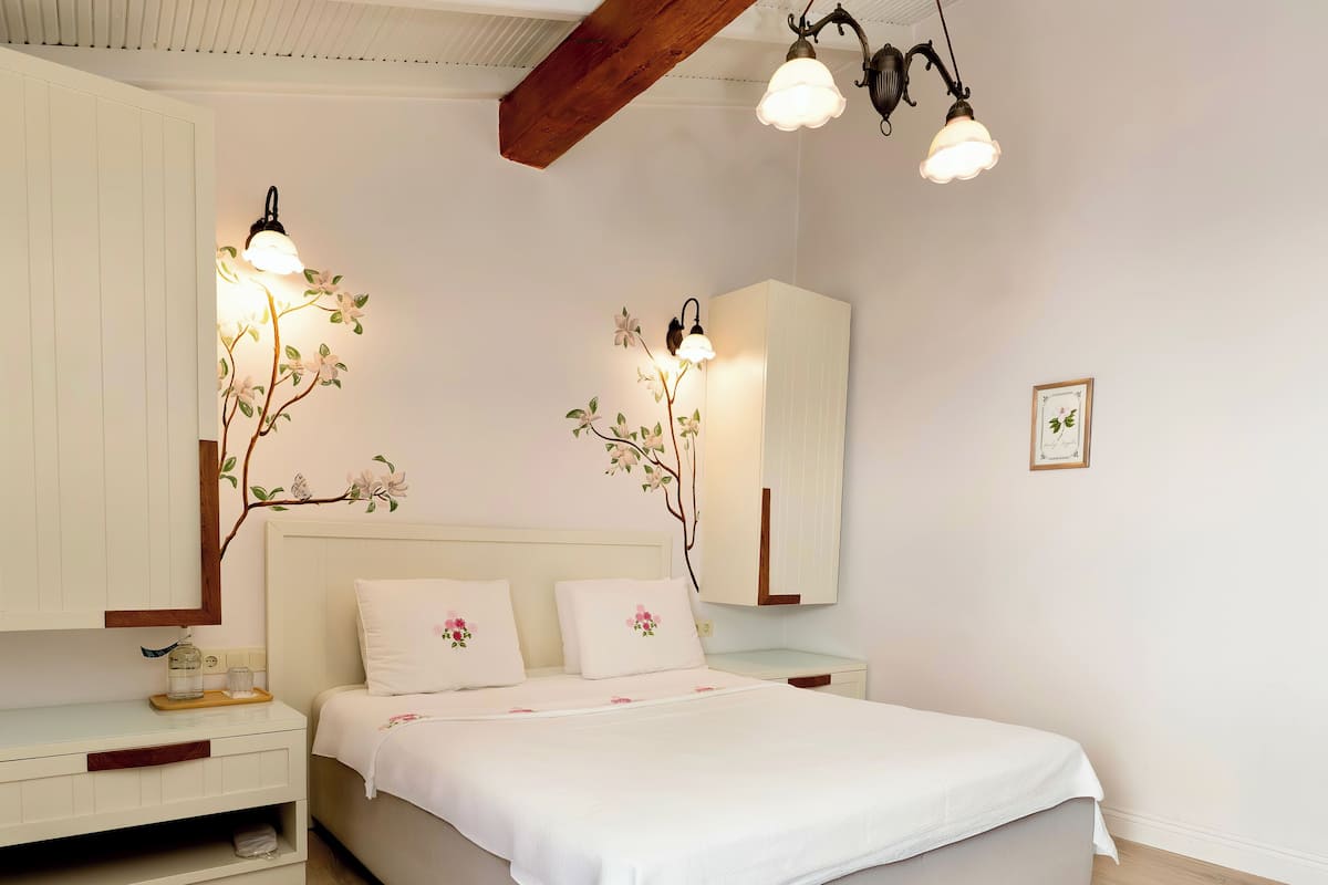 Un dormitorio con cama, mesitas de noche, cómoda y espejo.