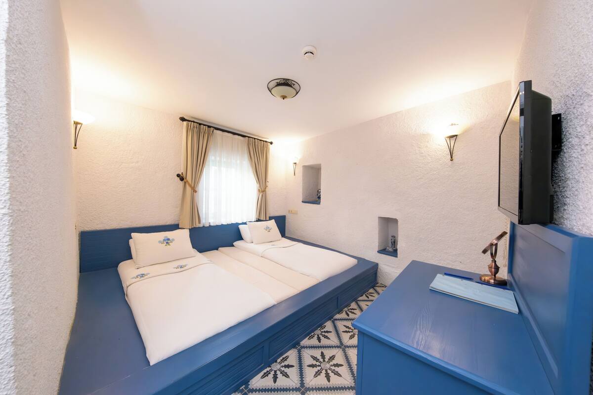 Un dormitorio con cama, mesita de noche y televisor.