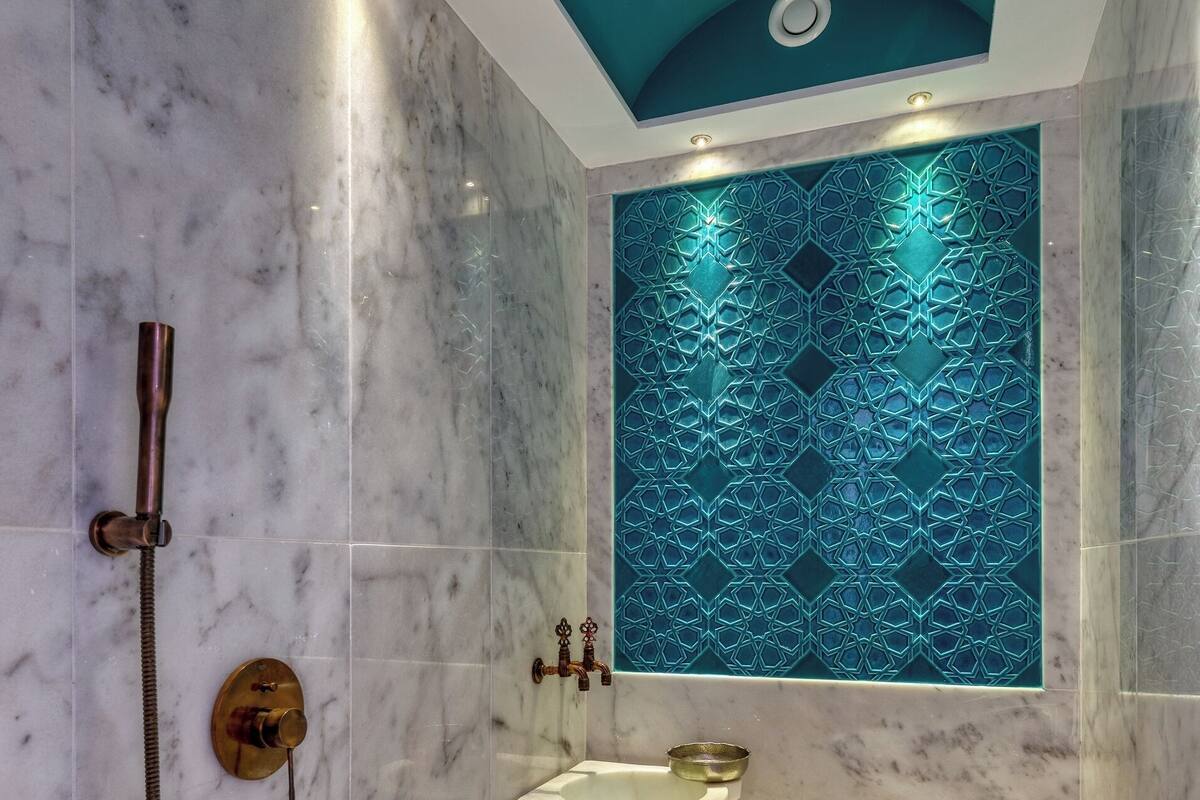 Un baño con ducha, lavamanos y un panel decorativo en la pared.