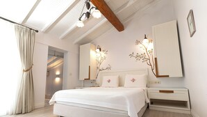 Un dormitorio con una cama grande, mesitas de noche, un armario y un techo con vigas a la vista y luminarias.