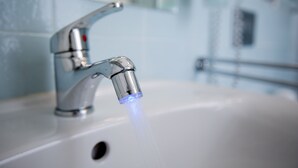 Un lavamanos de baño con un grifo moderno y agua corriente.