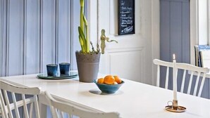 A dining area with a white table, chairs, a potted plant, and a candle. - Welcome Apartments (Jarfalla)