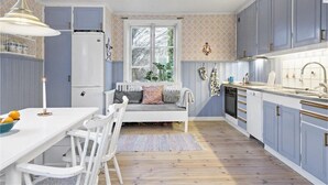 A kitchen with a white dining table, chairs, a bench, and a window with a view of greenery. - Welcome Apartments (Jarfalla)