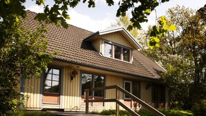 A two-story house with a sloped roof, large windows, and a wooden deck with stairs leading to the entrance. - Welcome Apartments (Jarfalla)