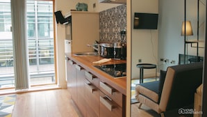 A modern kitchen with a wooden countertop, a coffee maker, and a built-in oven. - Homely Serviced Apartments - Blonk St (Sheffield)