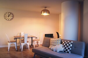 A living room with a sofa, two chairs, a table, and a wall clock.