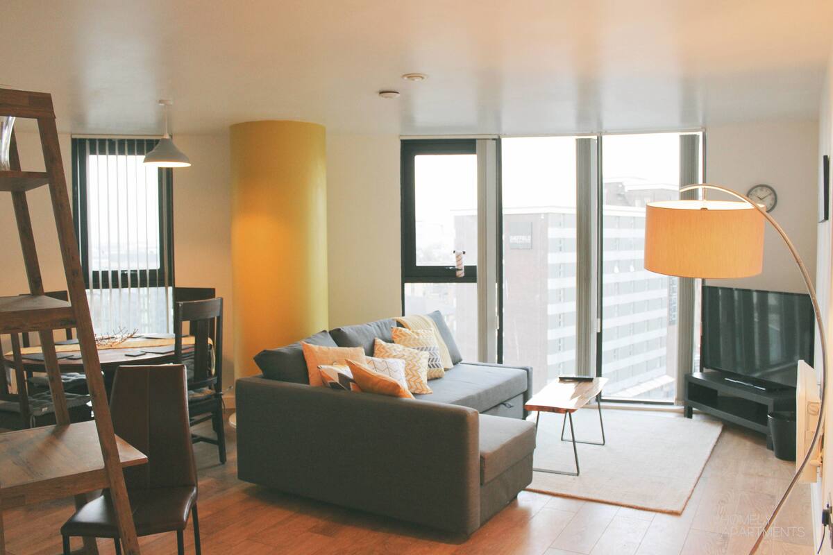 A modern living room with a sofa, chairs, a dining table, and a TV.