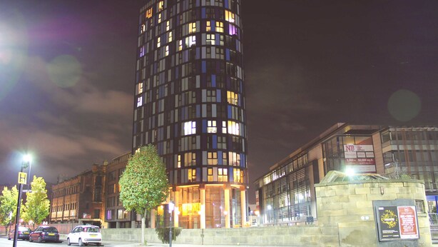 A modern hotel with a curved facade, multiple floors, and illuminated windows. - Homely Serviced Apartments - Blonk St (Sheffield)