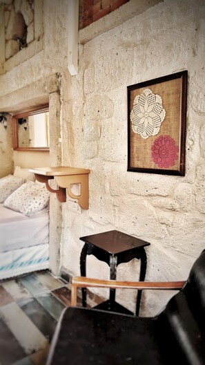 A rustic room with a bed, a small wooden table, and a wall-mounted shelf. - Lilyum Alaçatı Butik Otel (Cesme)